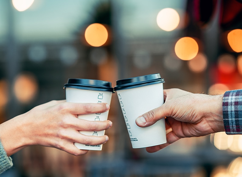 a couple is toasting with paper cup and drink coffee
